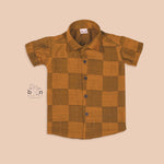 Mustard yellow silk shirt with golden checks, folded neatly beside a white veshti – premium boys’ traditional shirt from Boon Babies, Coimbatore.