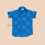 Royal blue silk shirt with golden check pattern, neatly folded beside a traditional white veshti – premium festive shirt for baby boys by Boon Babies, Coimbatore.