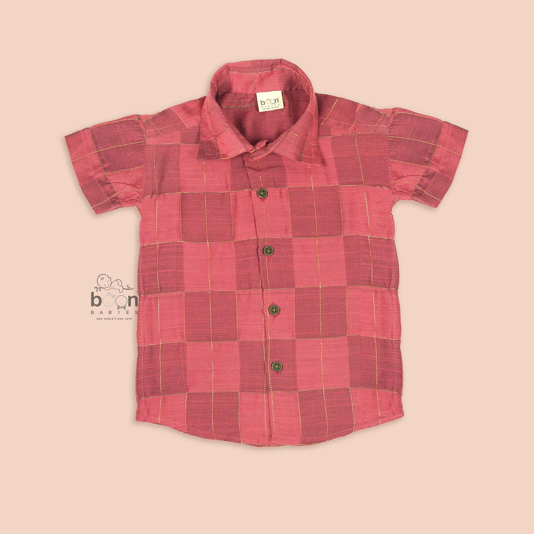 Folded rose pink silk shirt with golden grid pattern, placed beside a white veshti – boys' traditional festive wear from Boon Babies, Coimbatore.