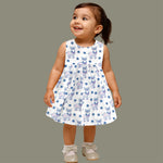 Baby girl wearing a white sleeveless frock with blue reindeer prints, made from slub cotton – part of the Boon Babies kidswear collection in Coimbatore.