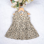 Leopard print sleeveless cotton frock for girls aged 12M–5Y, with a flared pleated skirt – displayed on a wooden hanger with white roses in the background.