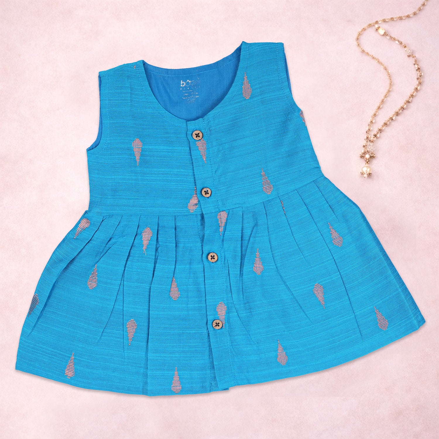 Baby girl wearing a blue ethnic sleeveless frock by Boon Babies, featuring traditional embroidery and comfortable fabric.