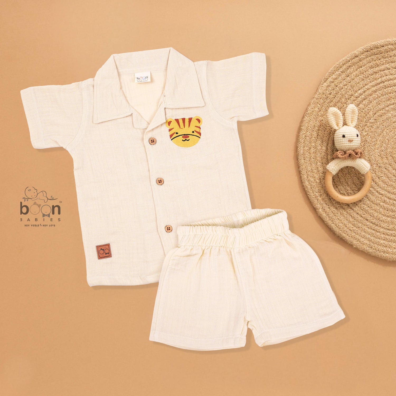 Cream crinkle muslin shirt and shorts set for boys featuring tiger face embroidery, open collar, and elastic shorts – from Boon Babies, Coimbatore.
