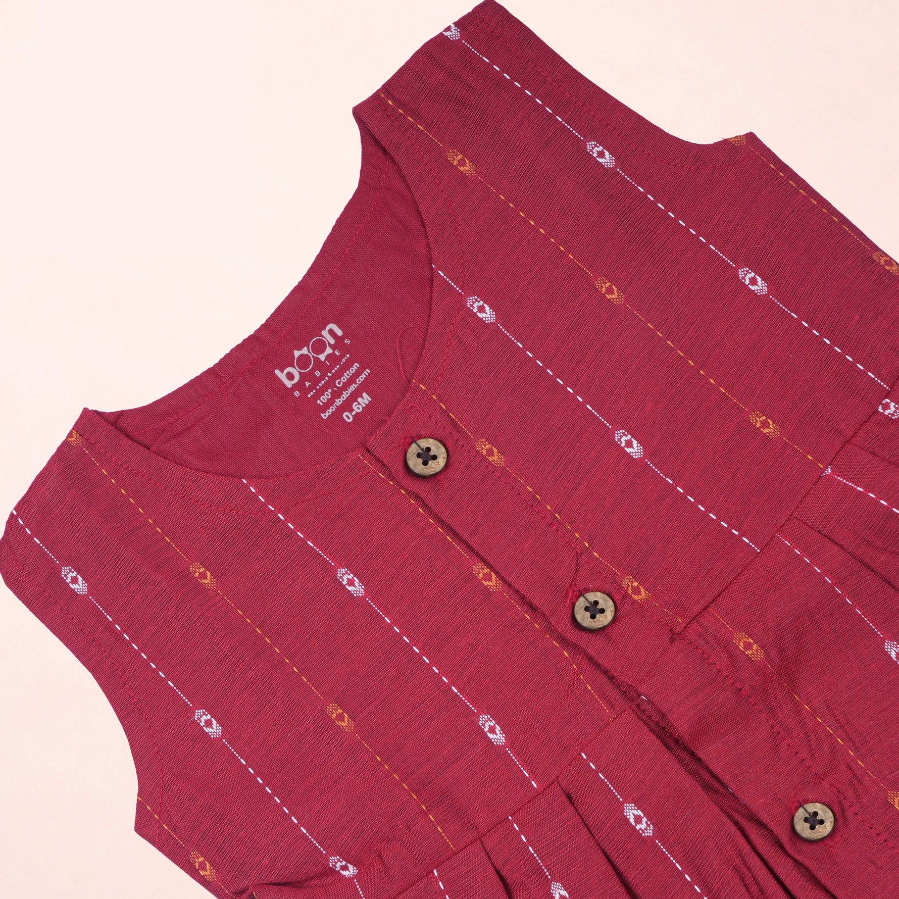 Baby girl wearing a cherry red ethnic sleeveless frock by Boon Babies, showcasing traditional design and vibrant color.