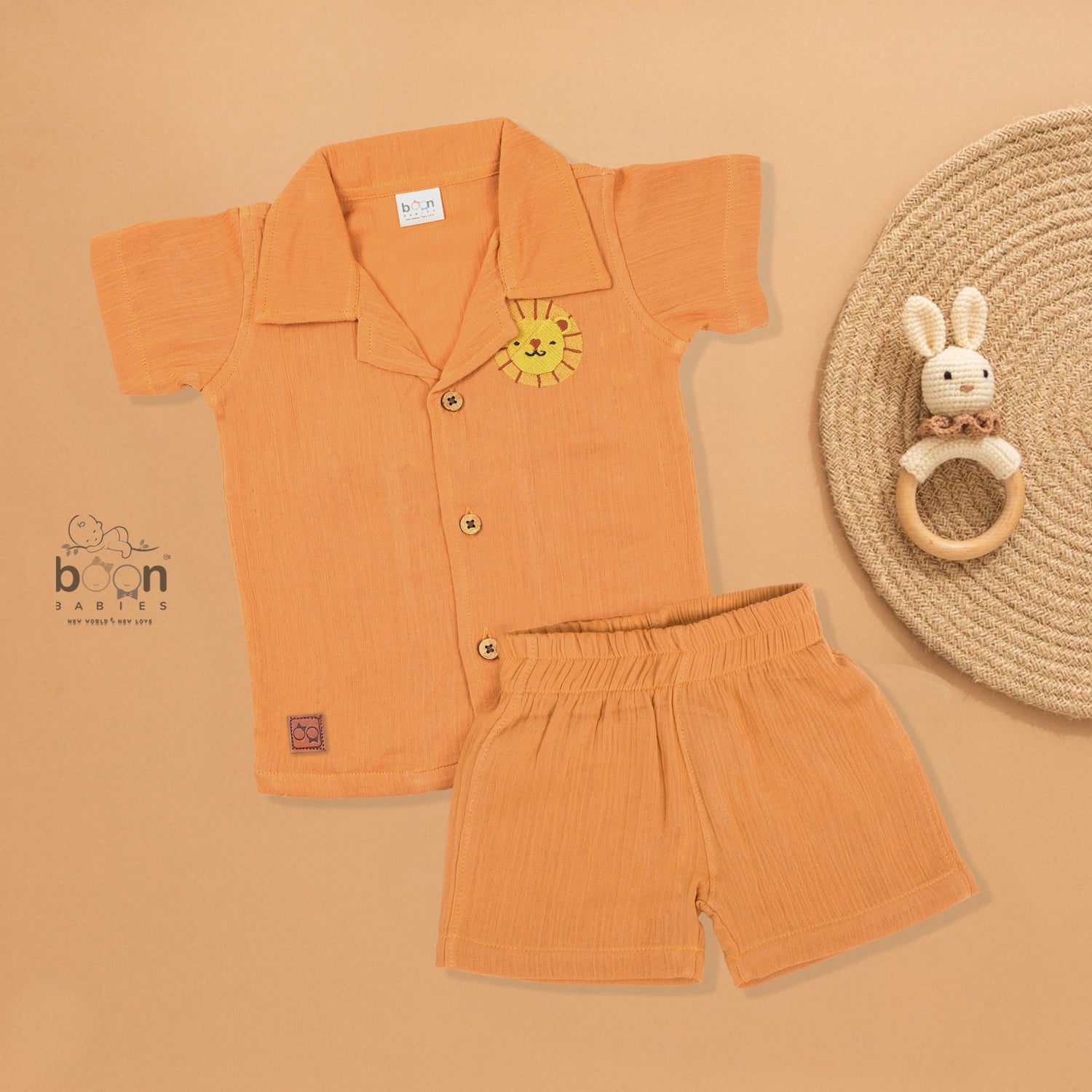 Orange crinkle muslin shirt and shorts set for boys with lion face embroidery, open collar, and elastic shorts – Boon Babies’ breathable summer wear from Coimbatore.

