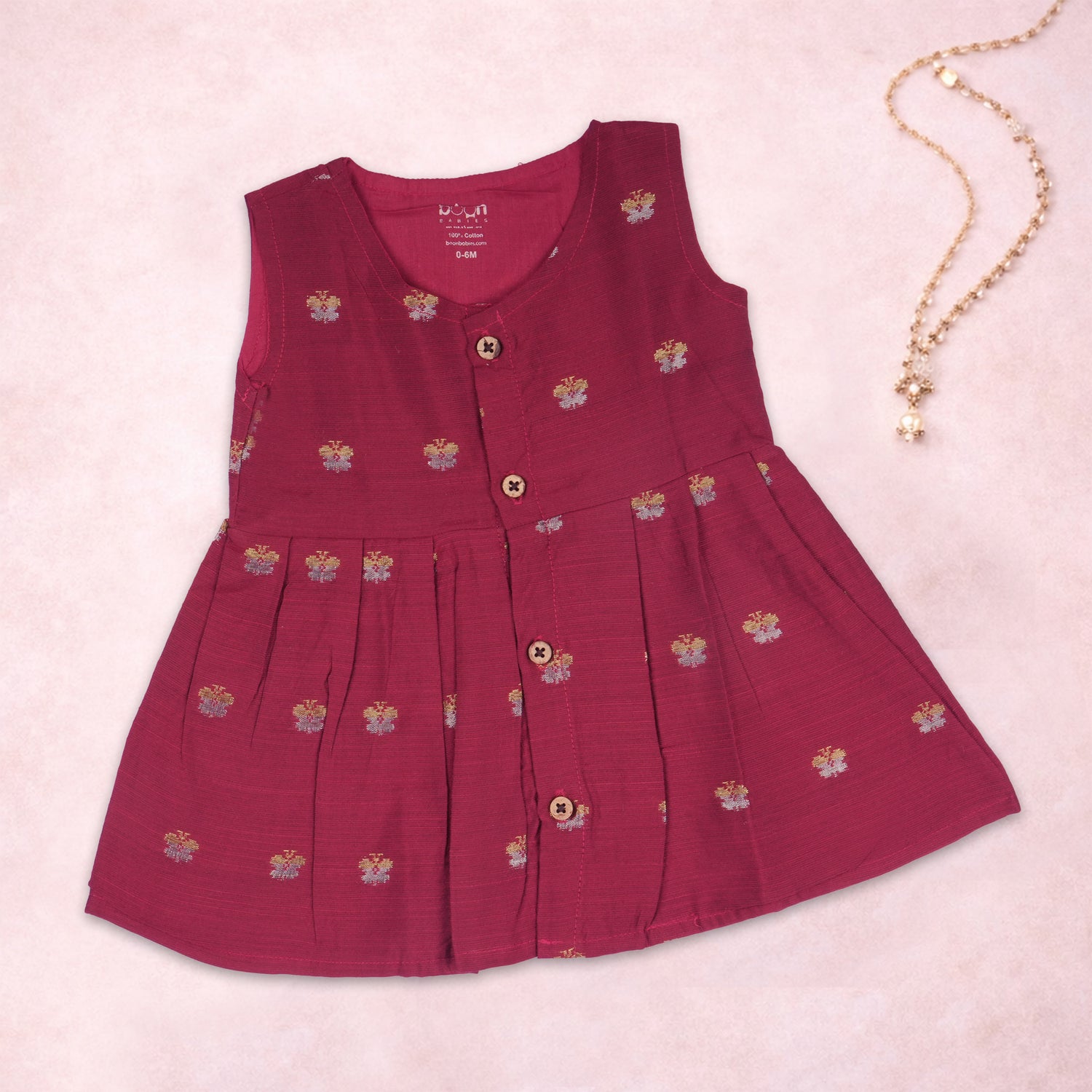 Baby girl wearing a red ethnic sleeveless frock from Boon Babies, featuring traditional design and vibrant fabric.