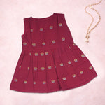 Baby girl wearing a red ethnic sleeveless frock by Boon Babies, featuring traditional embroidery and comfortable fabric.