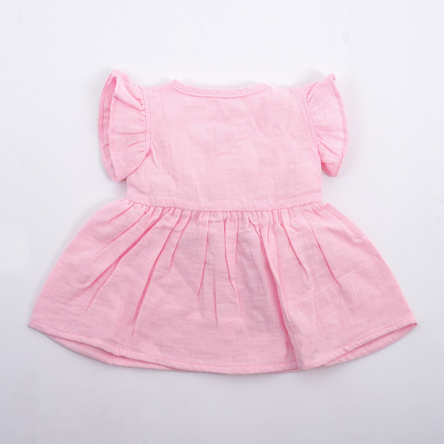 Baby girl in soft pink crinkled muslin solid frill frock by Boon Babies, showing the back view with ruffled details.