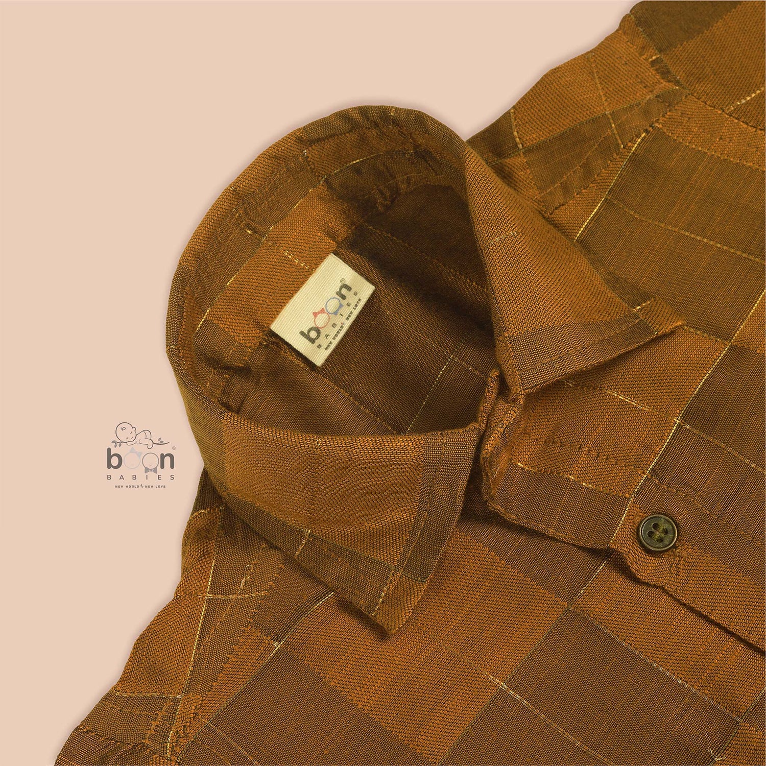 Mustard yellow silk shirt with golden checks, folded neatly beside a white veshti – premium boys’ traditional shirt from Boon Babies, Coimbatore.