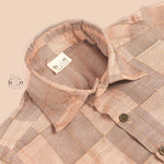 Pastel beige silk shirt with subtle golden checks, folded neatly beside a white veshti – premium boys’ ethnic shirt from Boon Babies, Coimbatore.