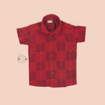 Rich red silk shirt with golden check pattern, folded neatly beside a white veshti – premium festive shirt for boys from Boon Babies, Coimbatore.