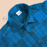 Royal blue silk shirt with golden check pattern, neatly folded beside a traditional white veshti – premium festive shirt for baby boys by Boon Babies, Coimbatore.