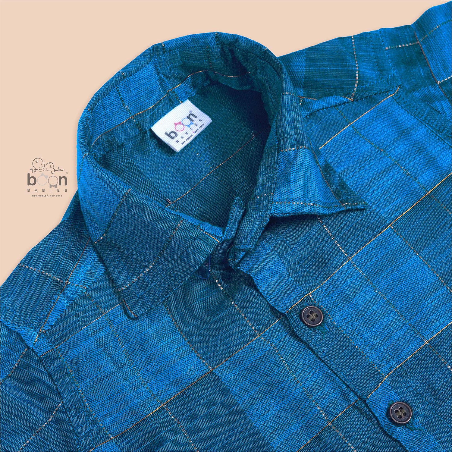 Royal blue silk shirt with golden check pattern, neatly folded beside a traditional white veshti – premium festive shirt for baby boys by Boon Babies, Coimbatore.