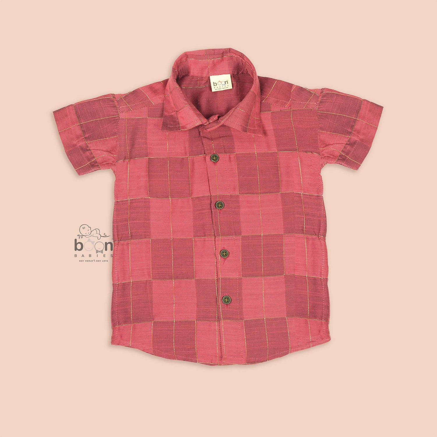 Folded rose pink silk shirt with golden grid pattern, placed beside a white veshti – boys' traditional festive wear from Boon Babies, Coimbatore.
