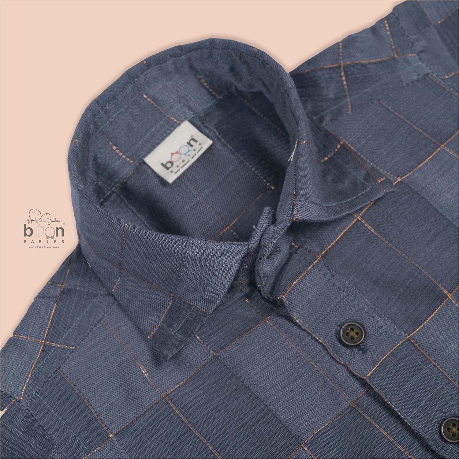 Folded slate grey silk shirt with subtle gold check design placed next to a traditional white veshti – boys’ festive ethnicwear by Boon Babies, Coimbatore.