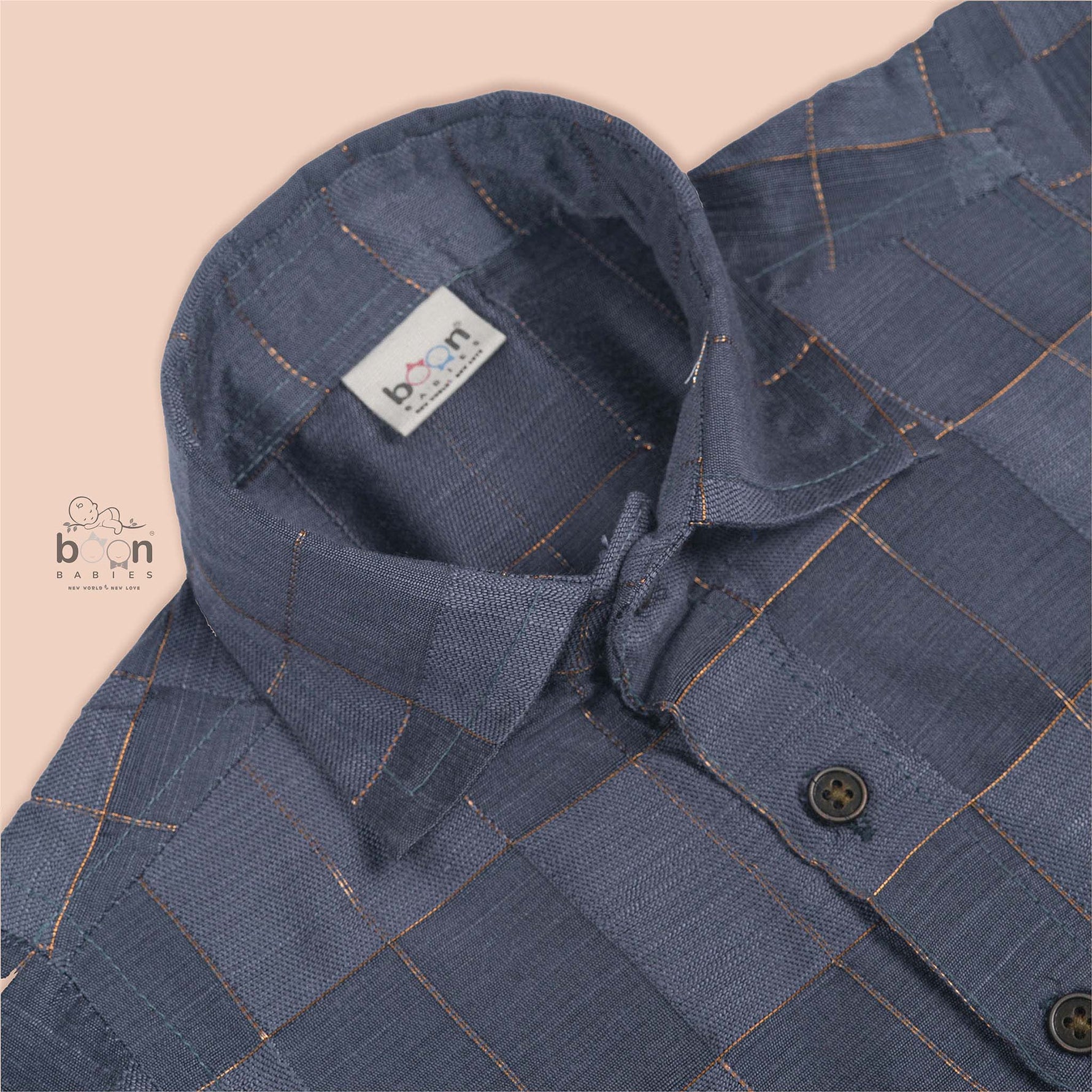 Folded slate grey silk shirt with subtle gold check design placed next to a traditional white veshti – boys’ festive ethnicwear by Boon Babies, Coimbatore.