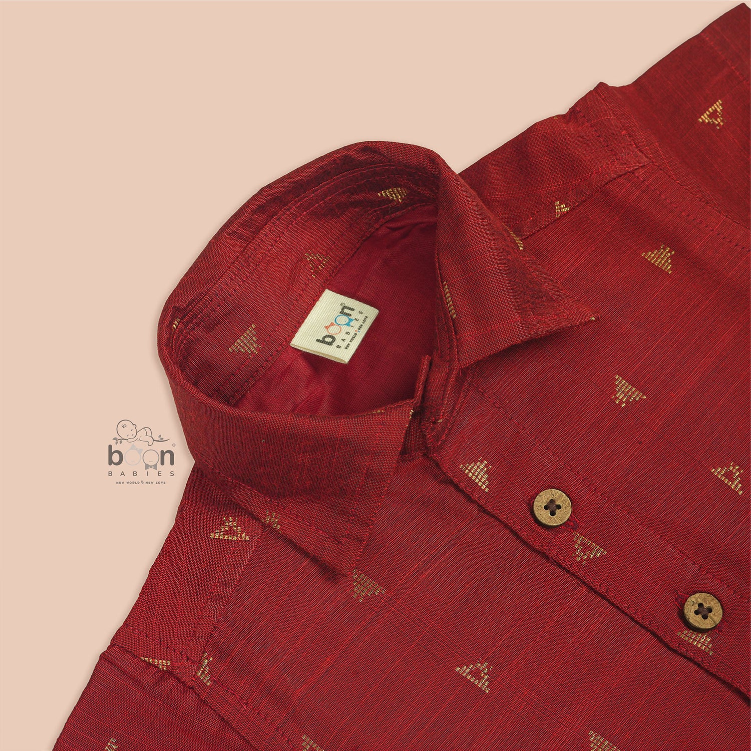 Red silk shirt for boys with gold triangle woven motifs, shown with white pattu dhoti – traditional outfit by Boon Babies.
