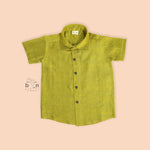 Boys lime green silk shirt with gold detailing, folded beside a white dhoti – festive kidswear set by Boon Babies.