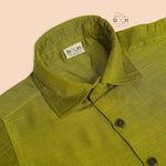 Boys lime green silk shirt with gold detailing, folded beside a white dhoti – festive kidswear set by Boon Babies.
