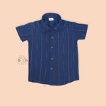 Boys navy blue silk shirt with subtle gold stripes, folded beside a white and gold pattu dhoti – Boon Babies festive wear.