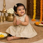 Baby girl in a sleeveless ivory ethnic frock by Boon Babies, featuring delicate embroidery and traditional design details.
