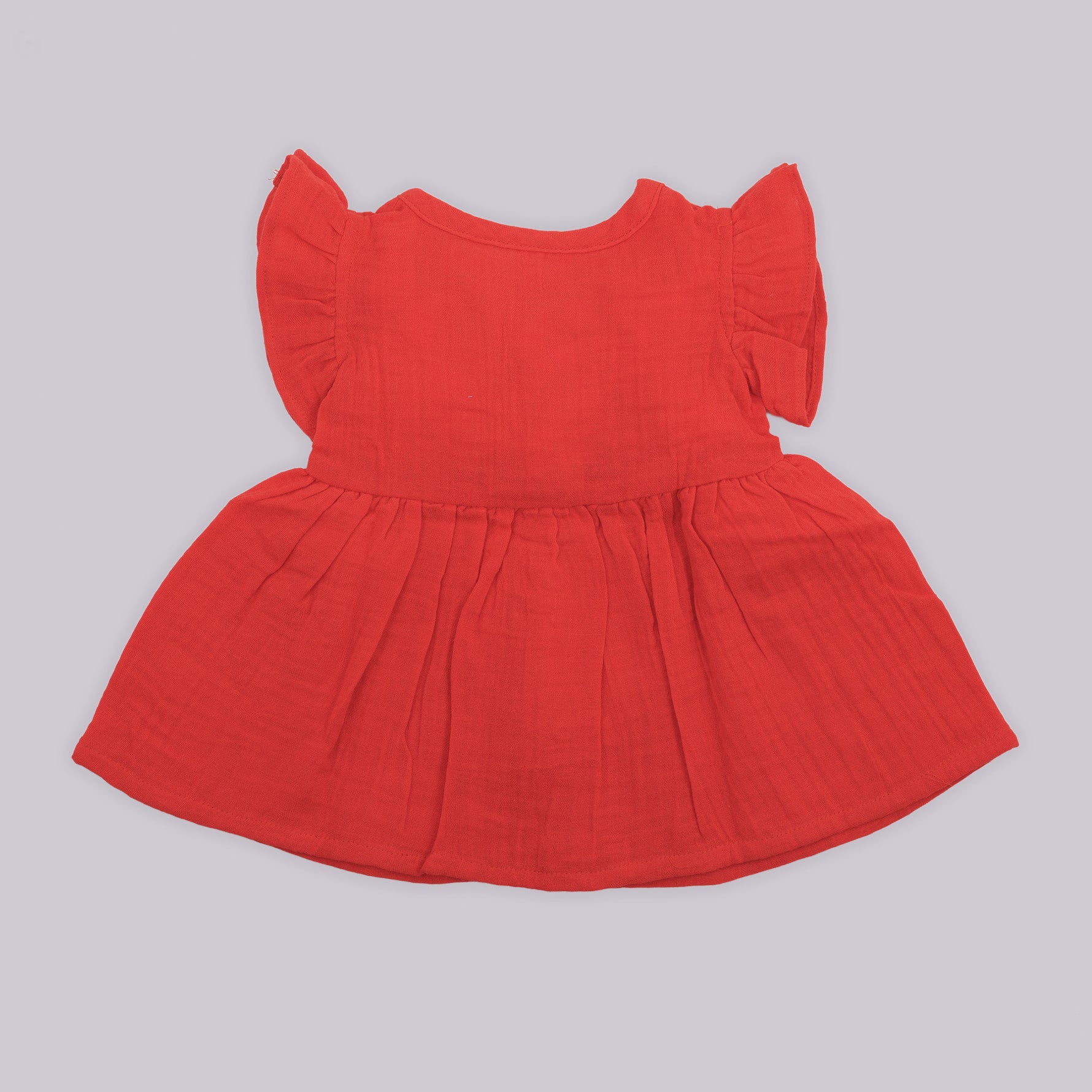 Back view of Boon Babies crinkled muslin frill frock for baby girls, featuring solid fabric and delicate frill details.