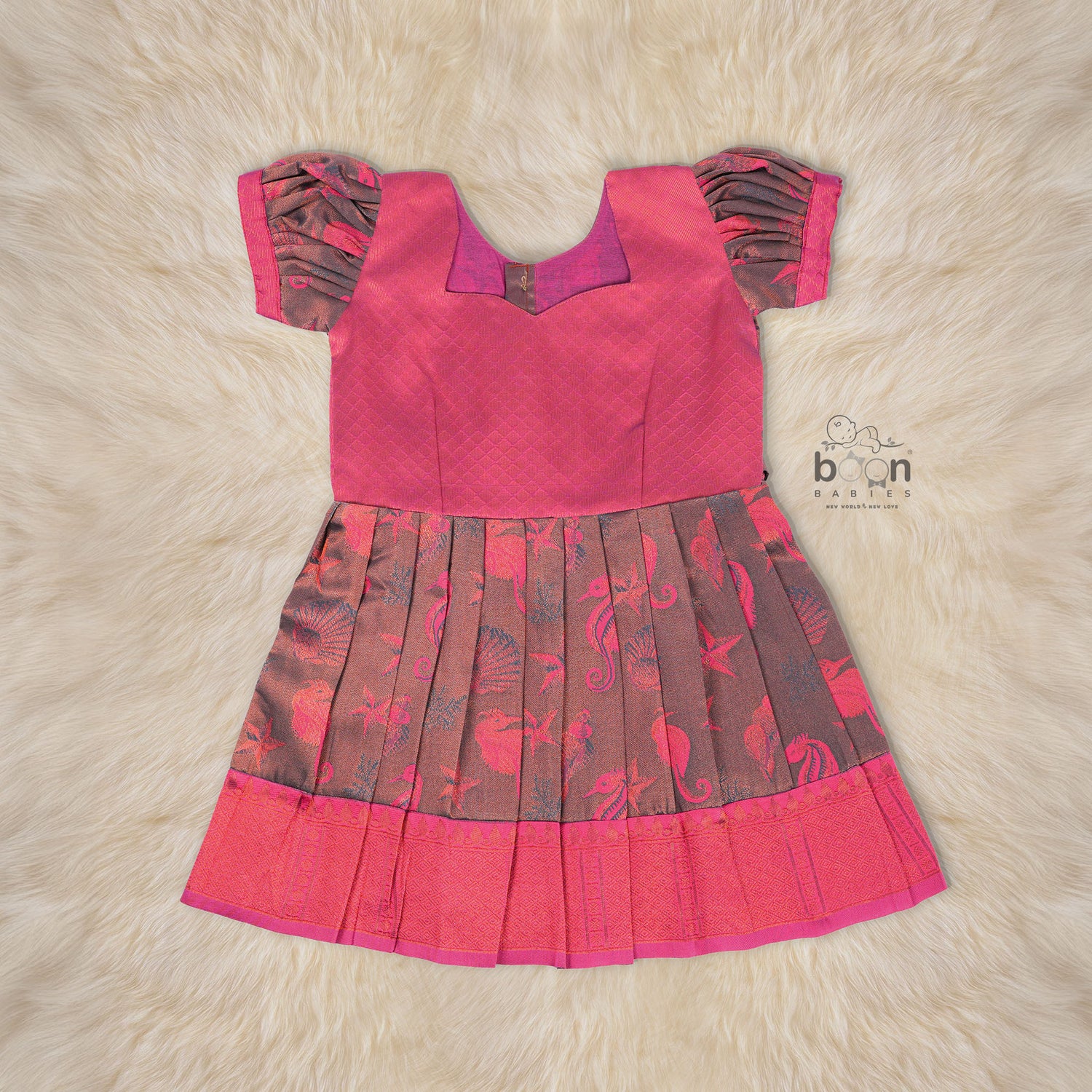 Traditional silk ethnic frock in Rani Pink and Brown for girls aged 1 to 5 years. Features zari motifs and puff sleeves – ideal for weddings and festivals.