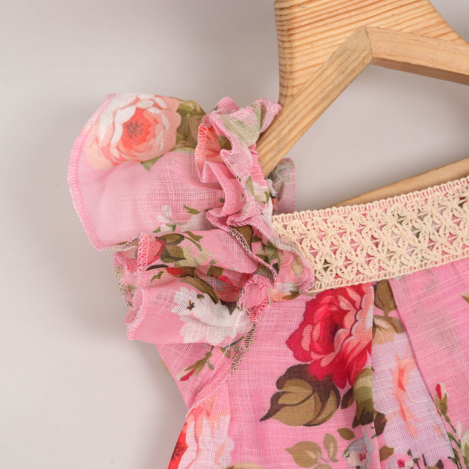 Chic dark pink linen frock with floral prints and ruffle sleeves. Sizes 6M–4Y. Ideal for festive and daily moments.
