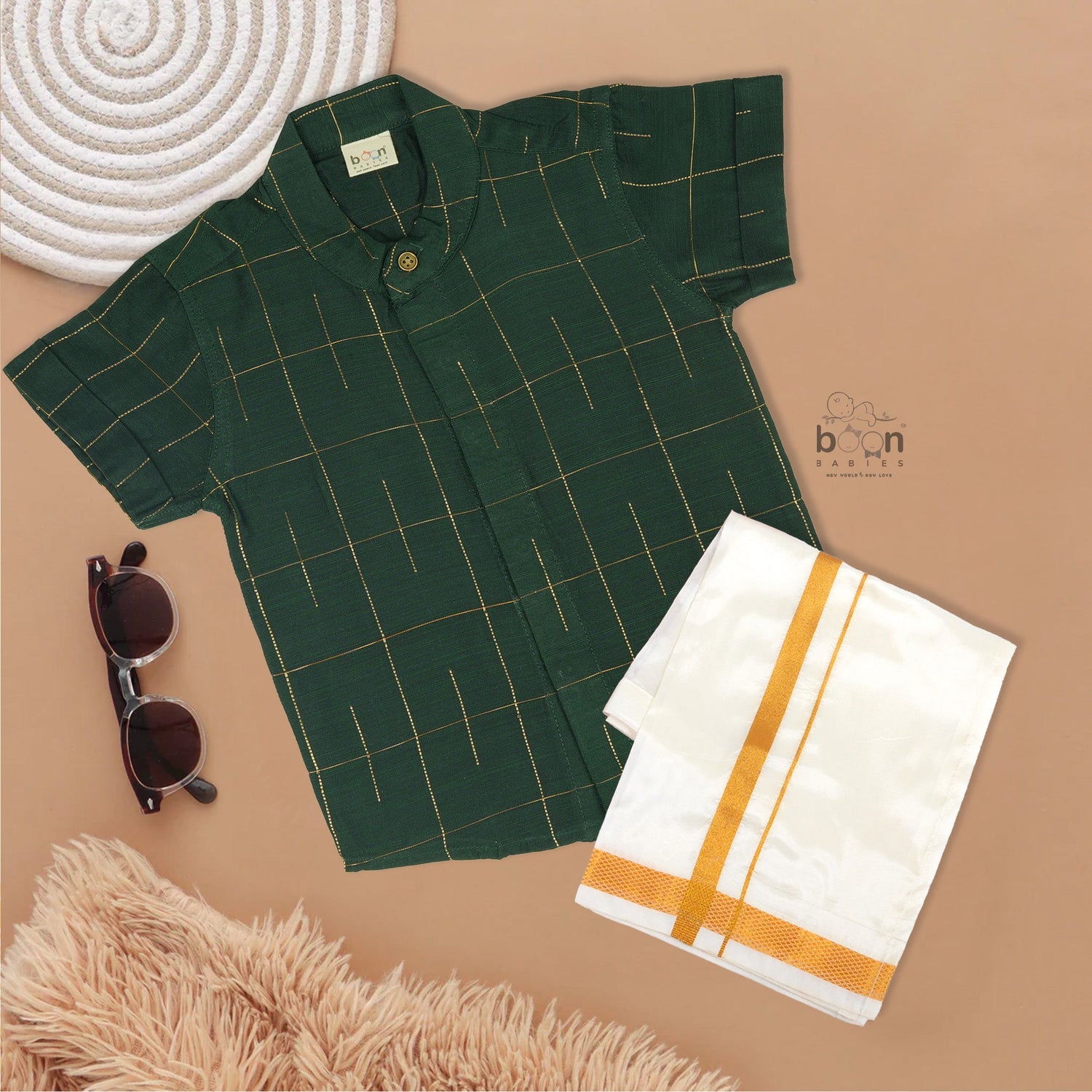 Dark green checked silk Chinese collar shirt with white dhoti and golden border – boys traditional wear flatlay by Boon Babies.
