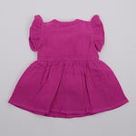 Back view of a baby's magenta-purple crinkled muslin solid frill frock by Boon Babies, featuring ruffled details and soft fabric.