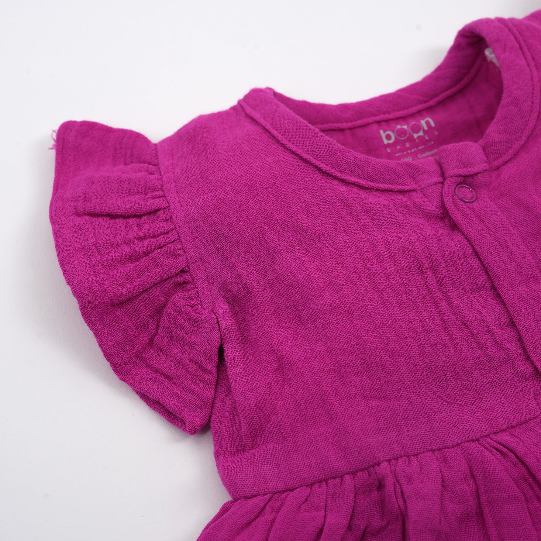 Baby girl wearing a Magenta Purple Crinkled Muslin Solid Frill Frock by Boon Babies, featuring ruffled details and soft fabric.