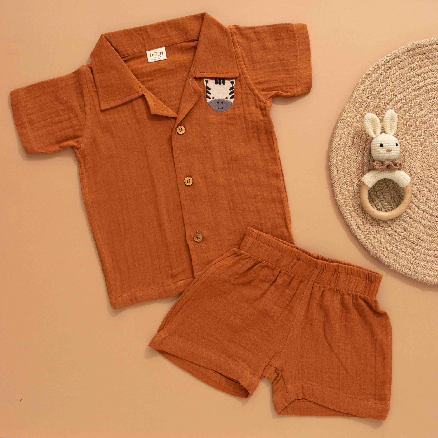 Rust brown boys’ shirt and shorts set made of soft crinkled muslin, with lion patch embroidery and wooden buttons – summer co-ord from Boon Babies.
