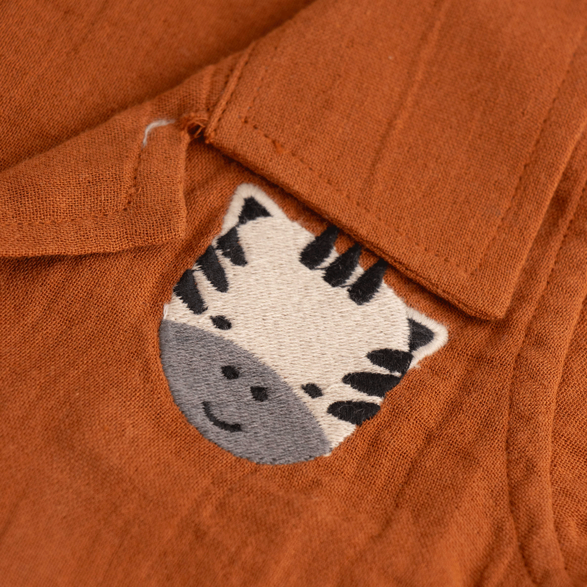 Rust brown boys’ shirt and shorts set made of soft crinkled muslin, with lion patch embroidery and wooden buttons – summer co-ord from Boon Babies.

