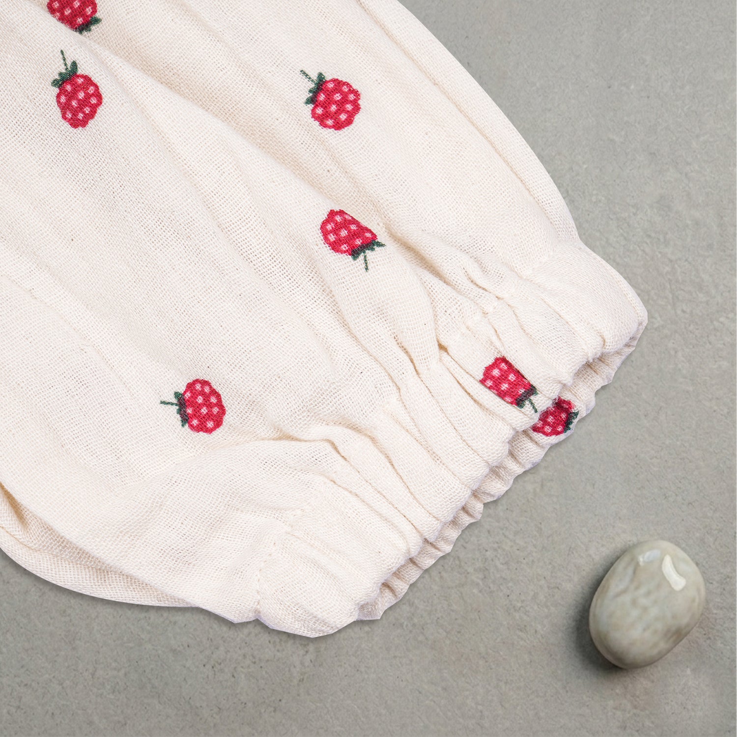 Baby girl wearing a printed muslin romper with frill sleeves by Boon Babies, showcasing soft fabric and cute design.
