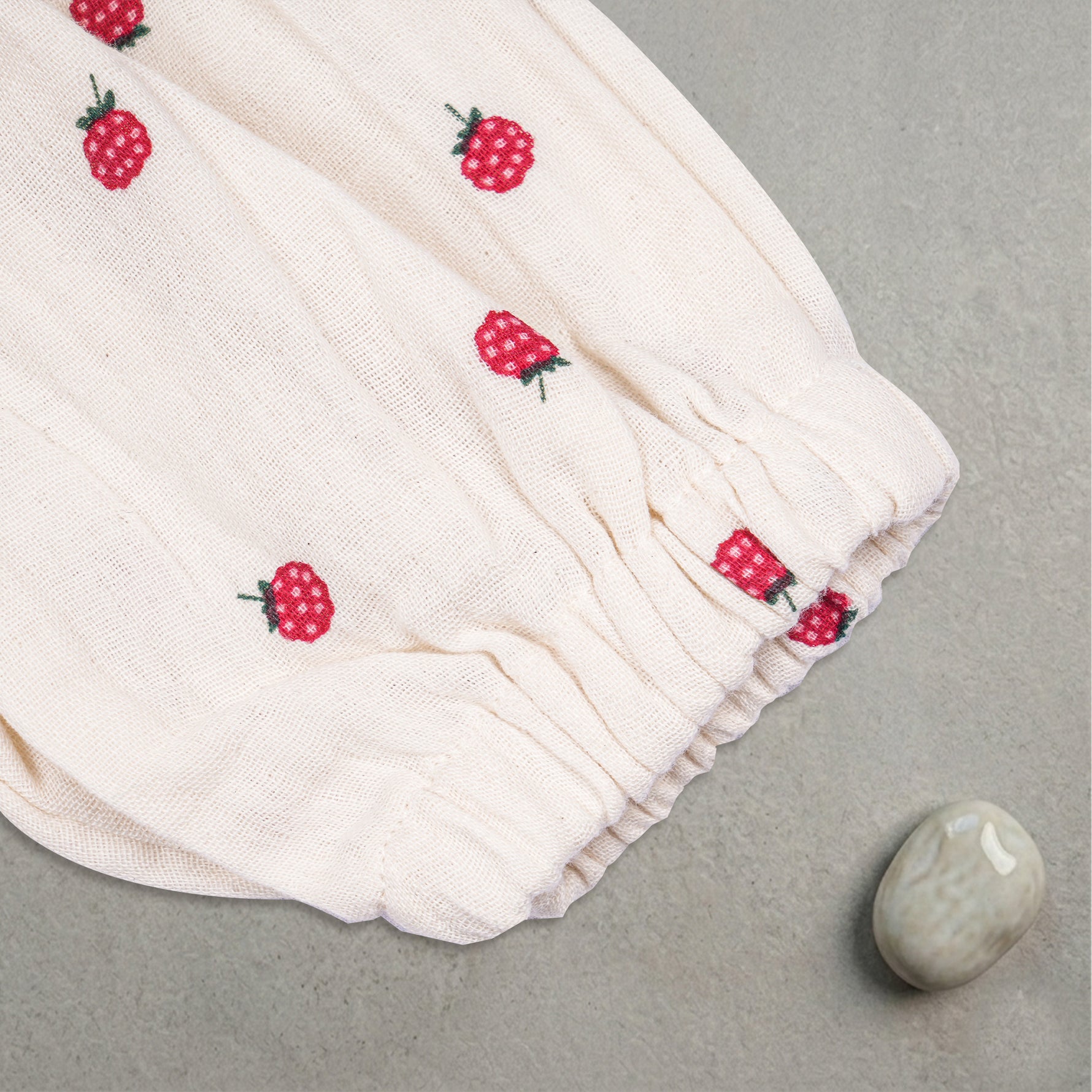 Baby girl wearing a printed muslin romper with frill sleeves by Boon Babies, showcasing soft fabric and cute design.