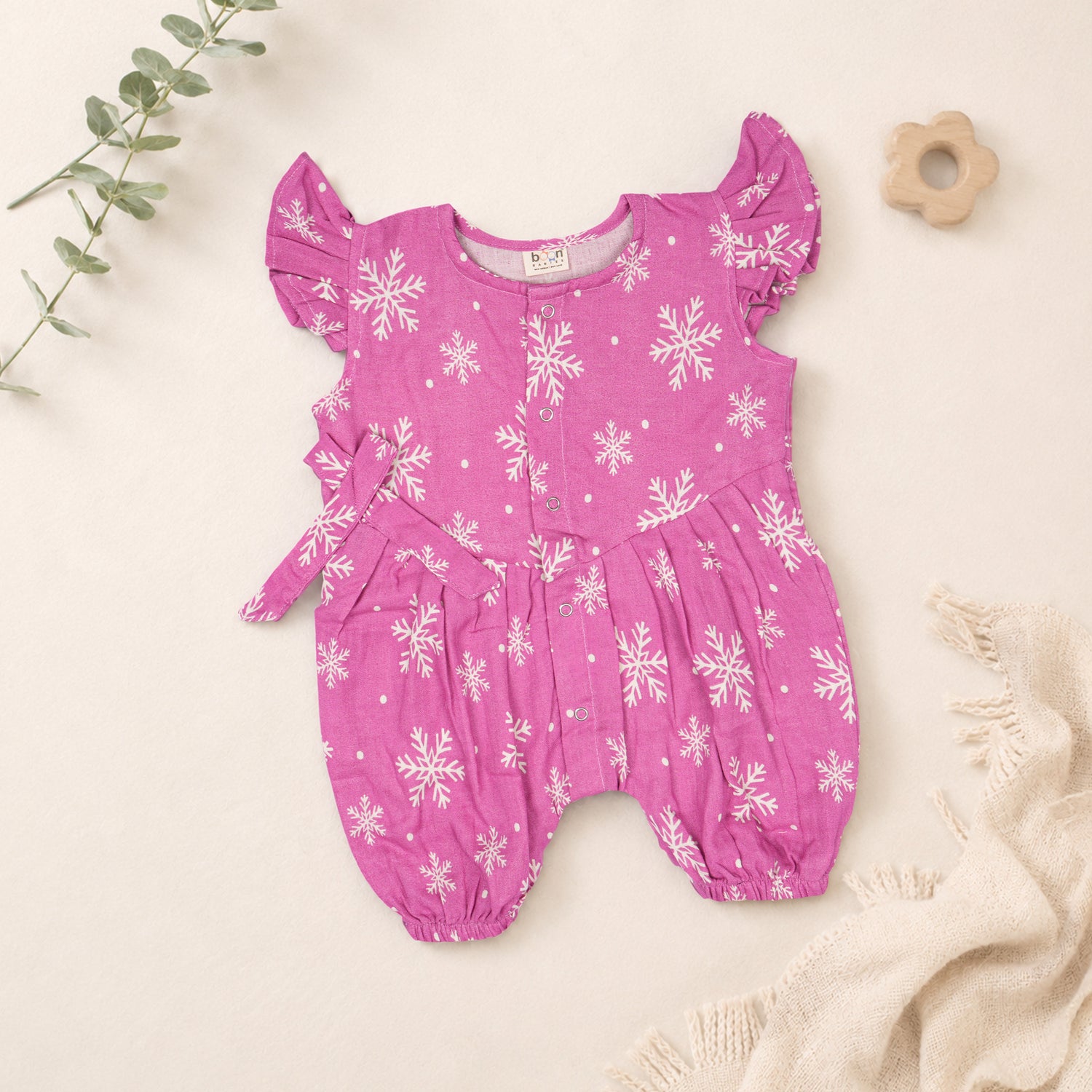 Baby girl in pink muslin printed romper with frill sleeves by Booon Babies, showing the adorable, soft fabric and cute design.