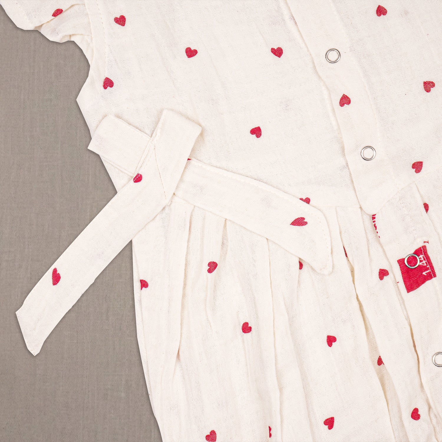 Baby girl in a printed muslin romper with frill sleeves from Boon Babies, showcasing soft fabric and adorable design.