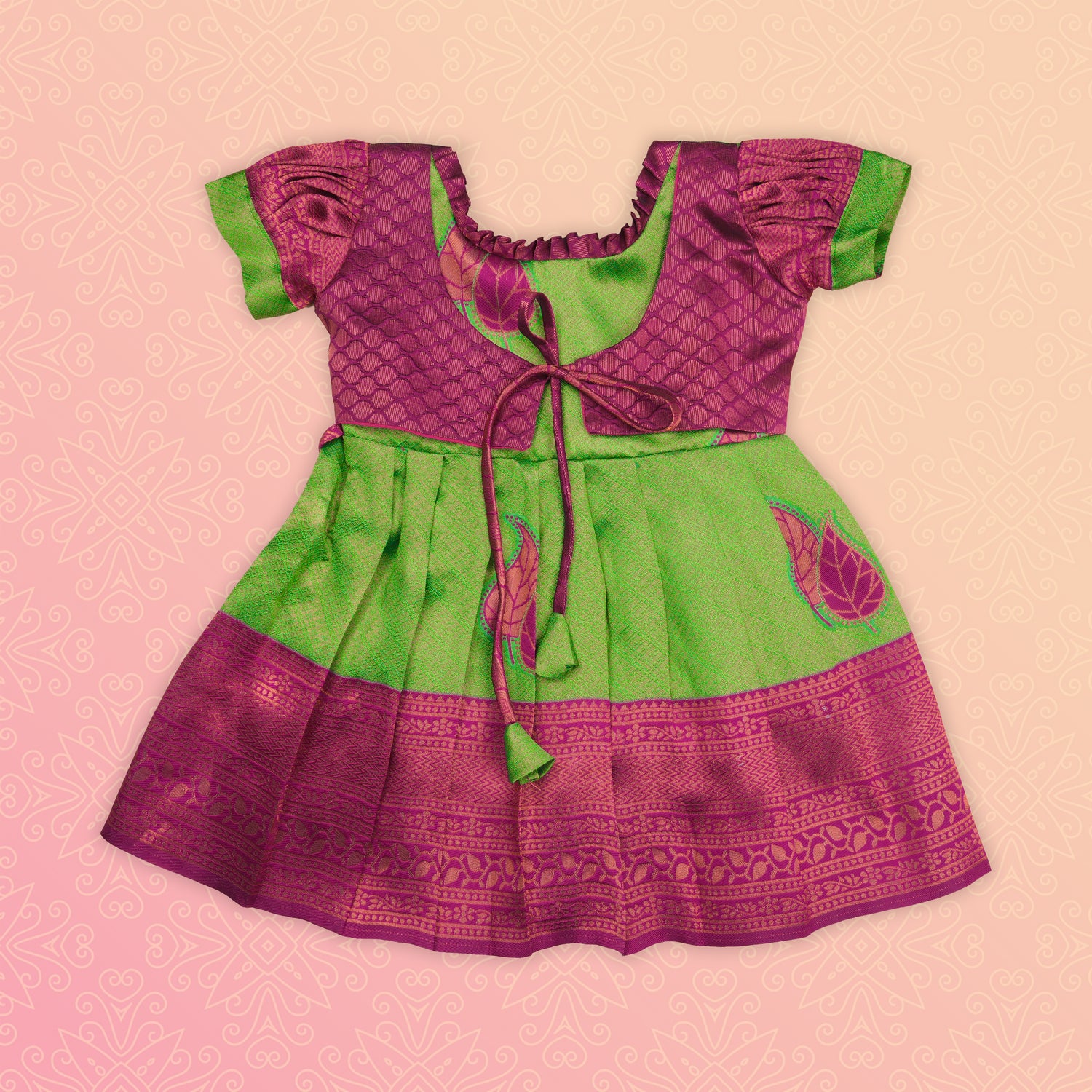 Girl wearing a green and pink tissue silk Pattu Pavadai ethnic frock by Boon Babies, showcasing traditional Indian attire.