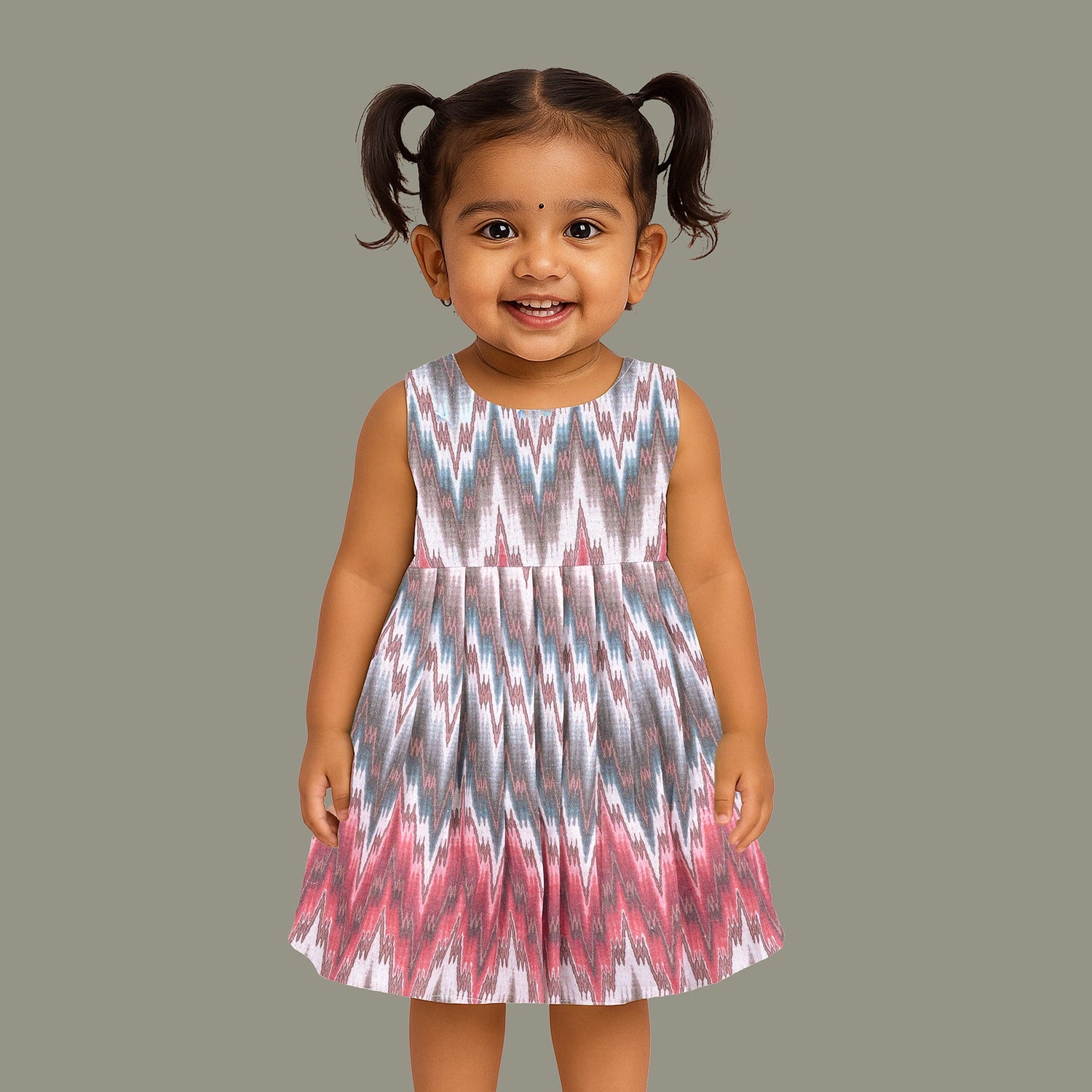 Girls’ sleeveless frock in multicolor Ikat print, made from cotton – displayed flat on white fur background with floral props – Boon Babies casual summer wear for girls aged 12M to 5Y.
