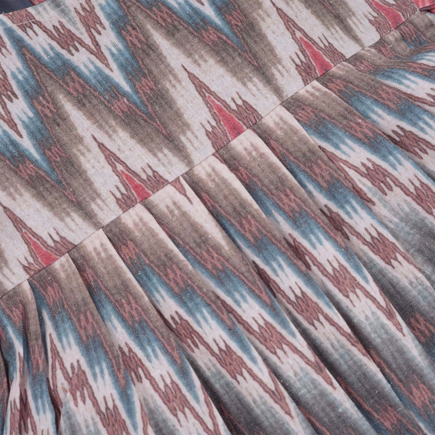 Girls’ sleeveless frock in multicolor Ikat print, made from cotton – displayed flat on white fur background with floral props – Boon Babies casual summer wear for girls aged 12M to 5Y.
