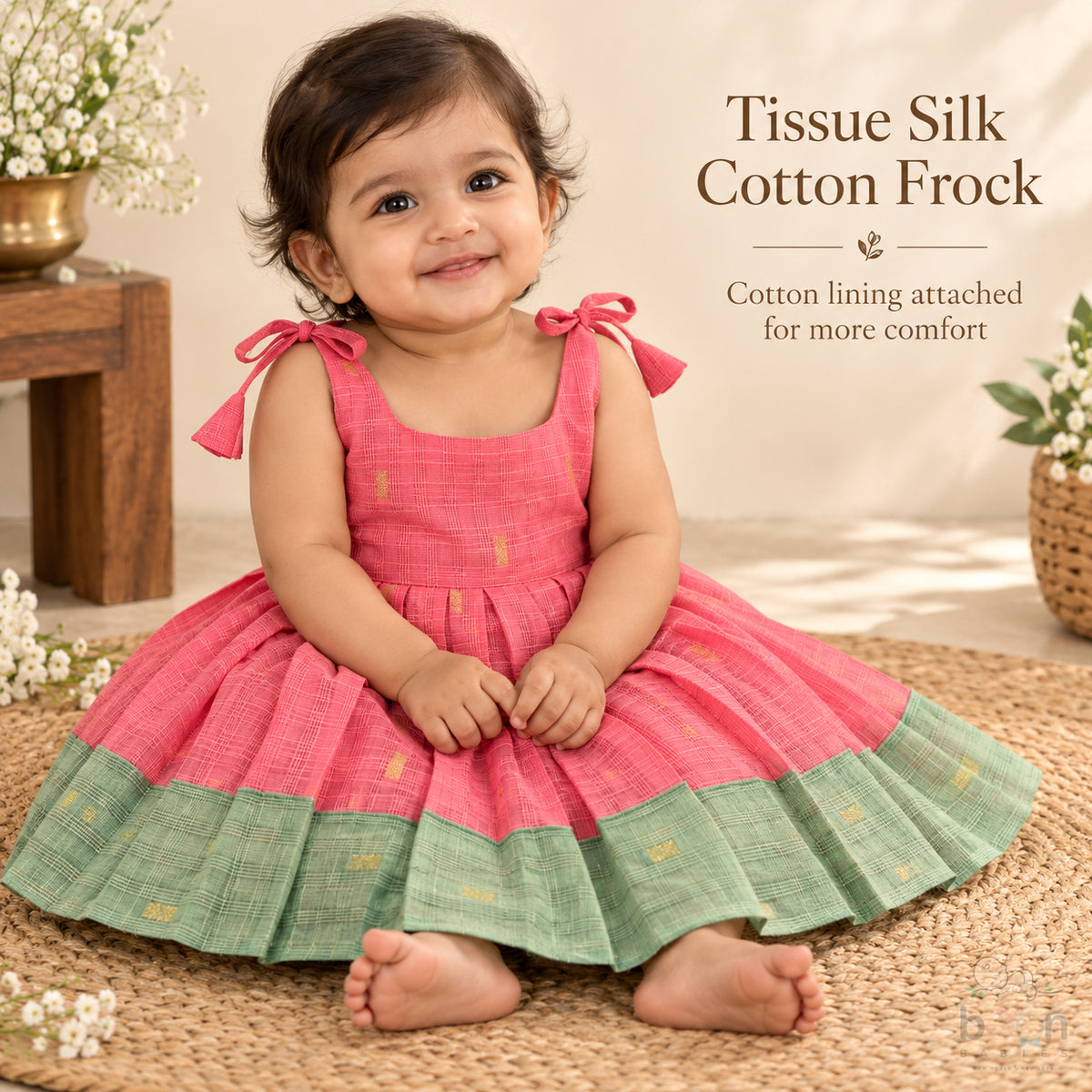 Baby girl wearing coral pink tissue silk cotton knot frock with sage green border and gold woven motifs