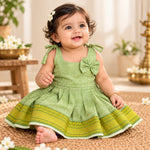 Baby girl wearing pastel green Mangalagiri cotton tie-shoulder frock with traditional green and yellow woven border