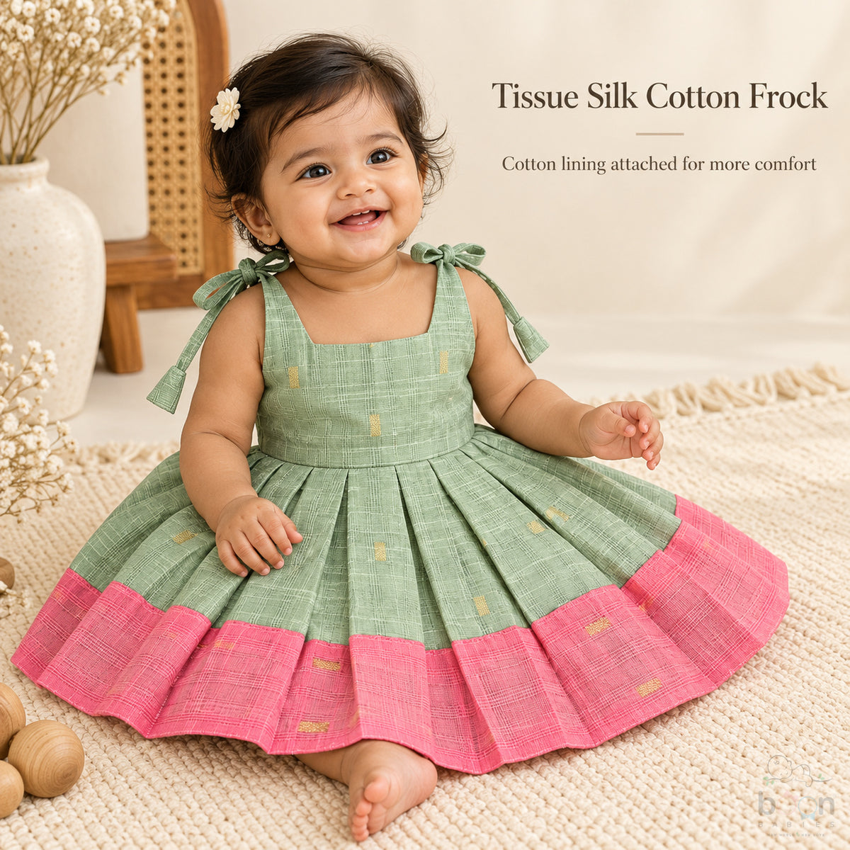 Baby girl wearing sage green tissue silk cotton knot frock with pink border and gold woven motifs