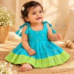 Baby girl wearing turquoise tissue silk cotton knot frock with lime green border and gold woven motifs