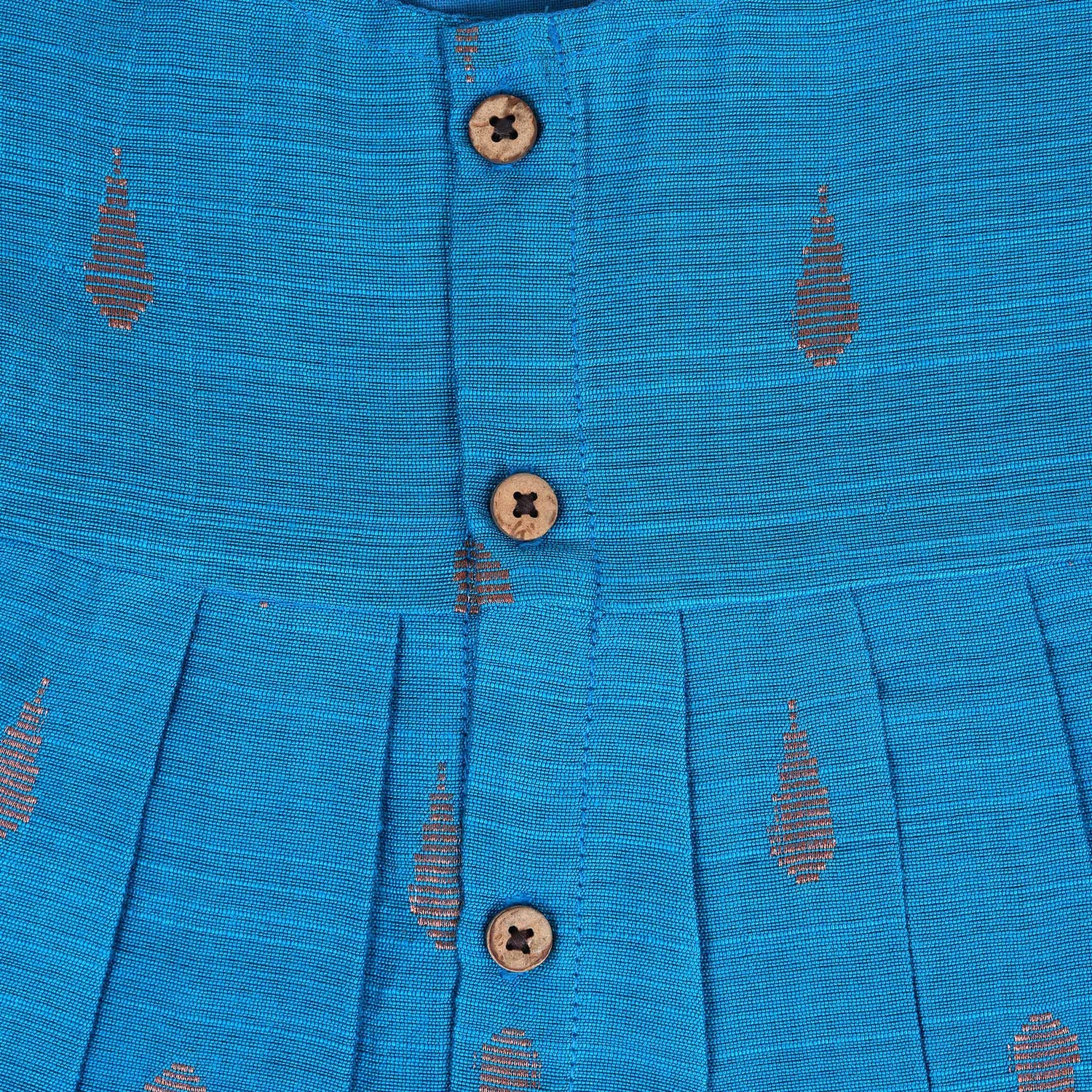 Blue silk sleeveless ethnic frock for baby girls with wooden buttons and traditional motifs, laid flat on a beige background with rustic and floral decor.