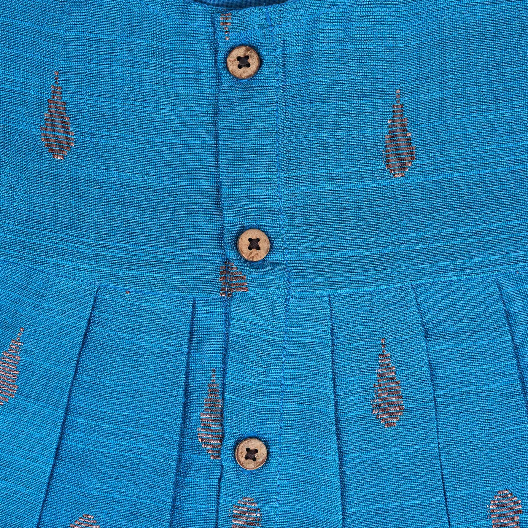 Blue silk sleeveless ethnic frock for baby girls with wooden buttons and traditional motifs, laid flat on a beige background with rustic and floral decor.