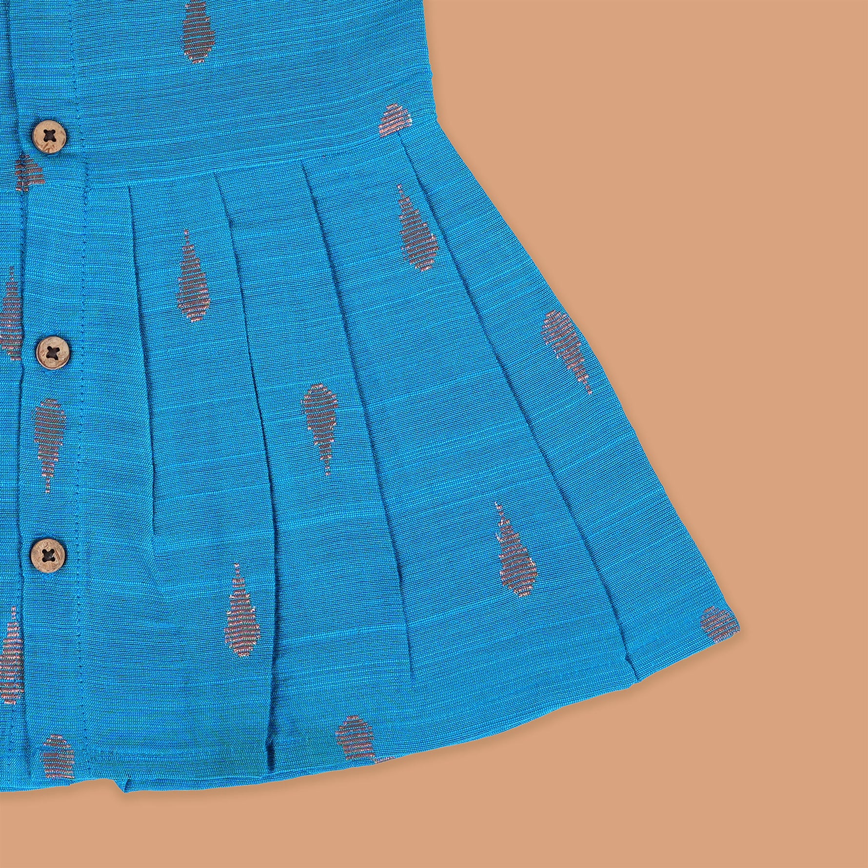 Blue silk sleeveless ethnic frock for baby girls with wooden buttons and traditional motifs, laid flat on a beige background with rustic and floral decor.