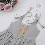 Festive grey silk Onam knot frock with triangle yoke design & zari border. Perfect for baby girls (0–12M).