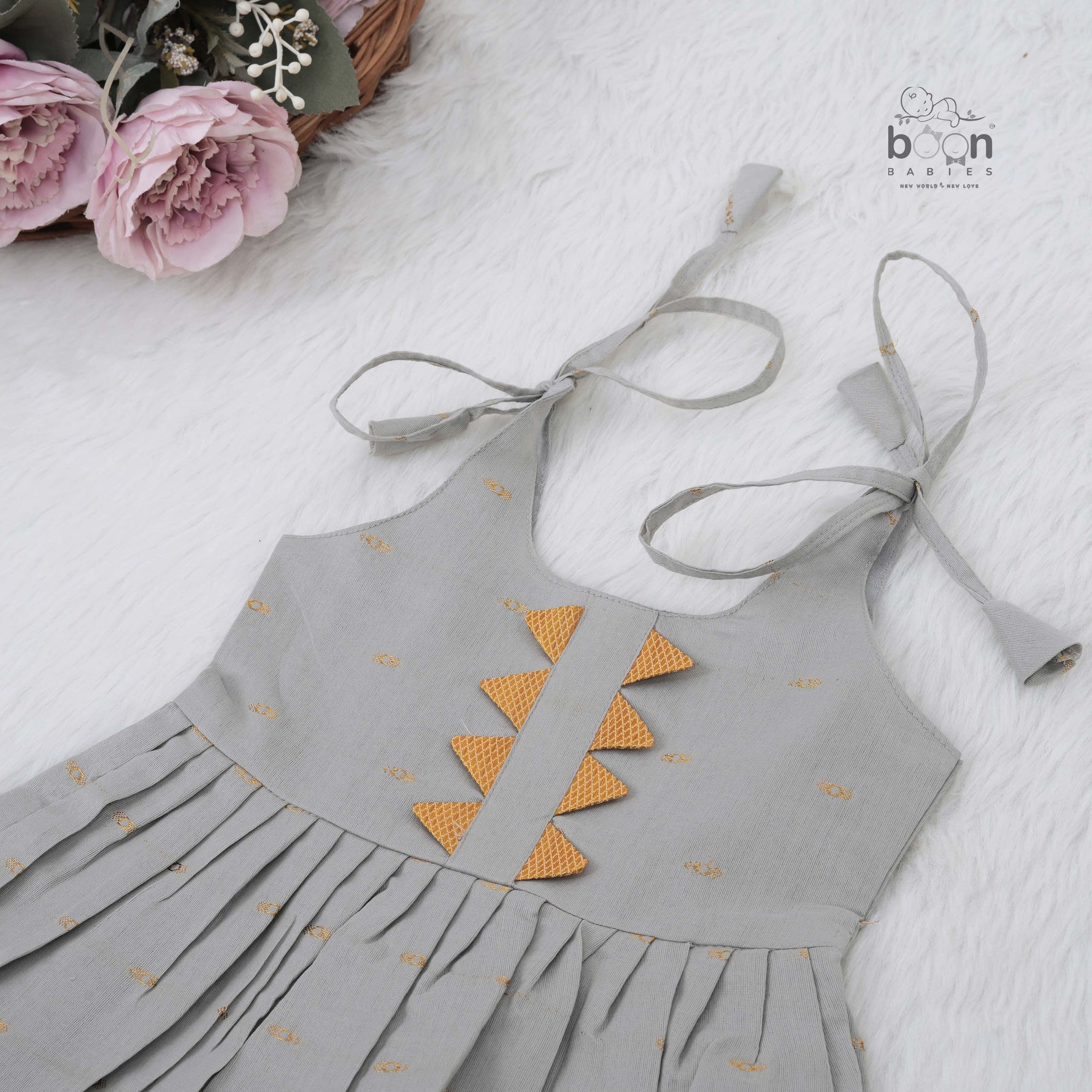 Festive grey silk Onam knot frock with triangle yoke design & zari border. Perfect for baby girls (0–12M).