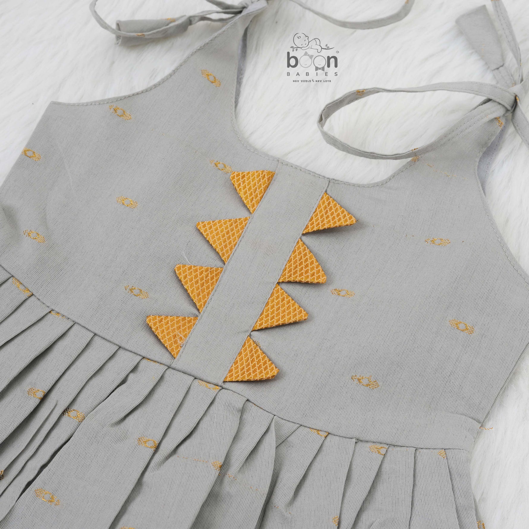 Festive grey silk Onam knot frock with triangle yoke design & zari border. Perfect for baby girls (0–12M).